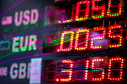 Painel eletrônico exibe cotações e variações de moedas como dólar, euro e libra em um ambiente de mercado financeiro.