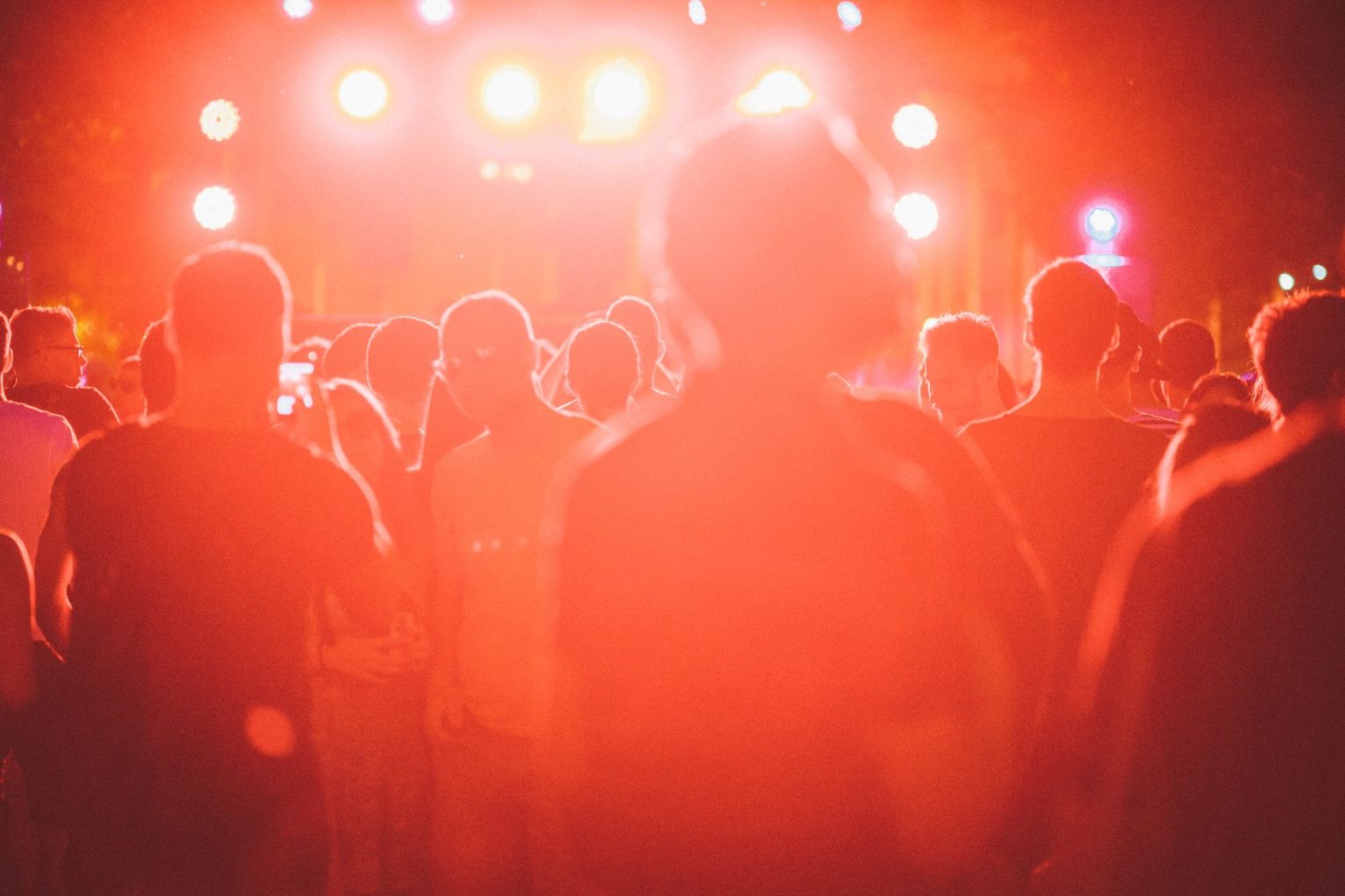 Público reunido em um festival de música ao ar livre, diante de um palco iluminado.