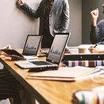 Pessoas reunidas em um escritório durante uma discussão de trabalho diante de um computador