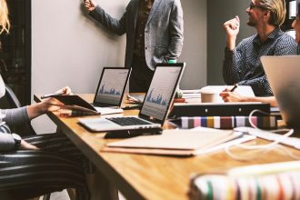 Pessoas reunidas em um escritório durante uma discussão de trabalho diante de um computador