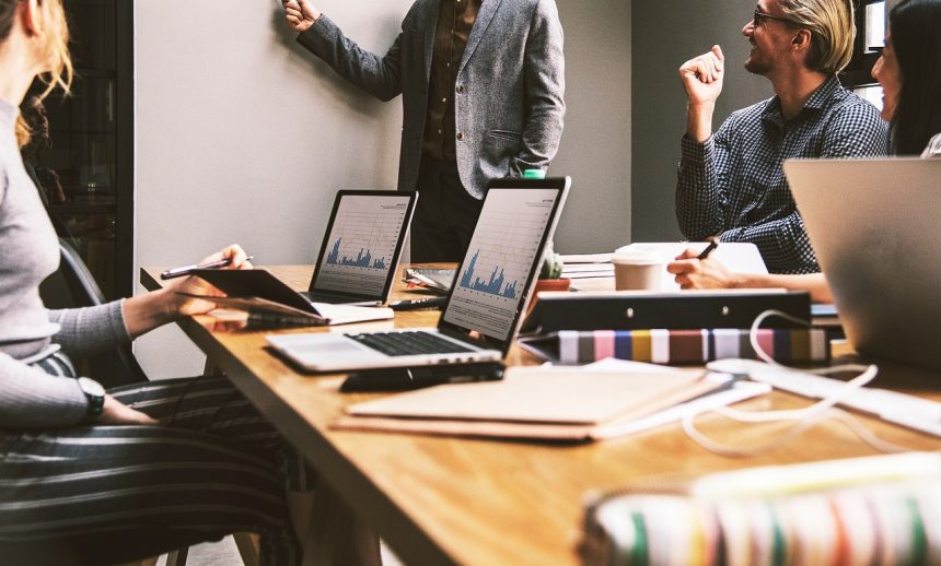 Pessoas reunidas em um escritório durante uma discussão de trabalho diante de um computador